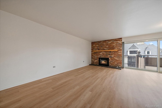 700 N Washington St Unit 402, Denver, CO 80203 - unfurnished living room featuring light wood-type flooring and a brick fireplace