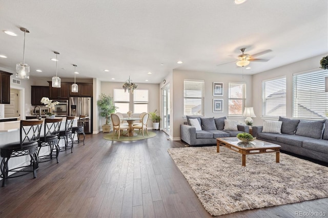 living room with dark hardwood / wood-style floors, sink, and ceiling fan with notable chandelier