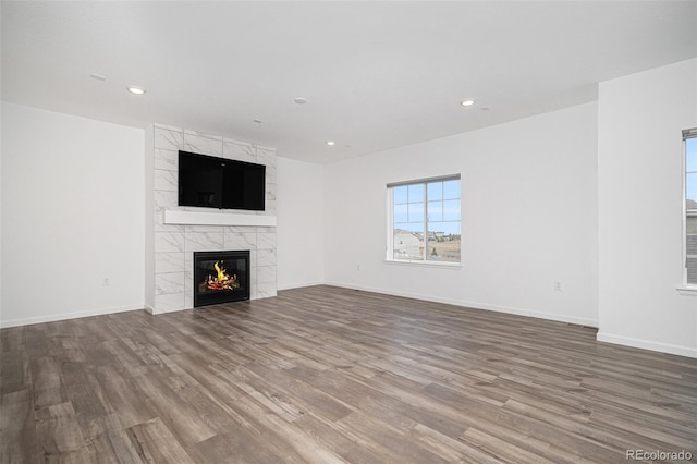 unfurnished living room featuring baseboards, a tile fireplace, wood finished floors, and recessed lighting