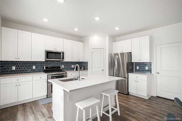 kitchen with a center island with sink, white cabinetry, dark wood-type flooring, sink, and stainless steel appliances