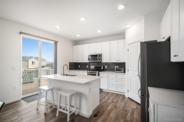 kitchen featuring sink, stainless steel appliances, dark hardwood / wood-style floors, white cabinets, and a center island with sink