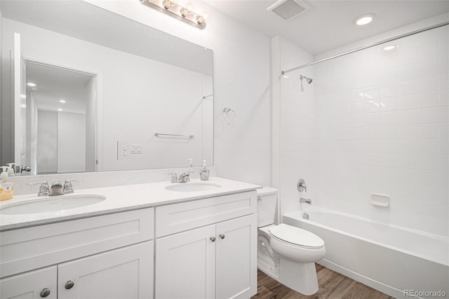 full bathroom featuring tiled shower / bath, vanity, hardwood / wood-style flooring, and toilet