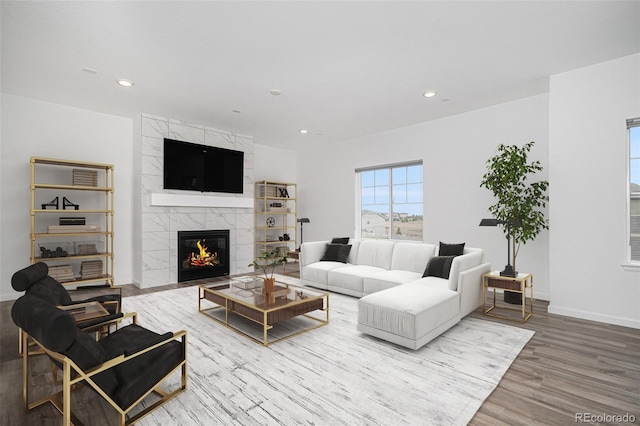 living room featuring recessed lighting, wood finished floors, a tiled fireplace, and baseboards
