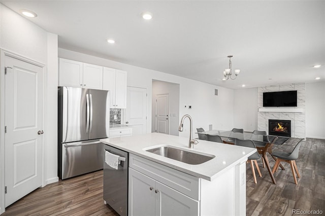 kitchen featuring a large fireplace, stainless steel appliances, dark wood-style floors, and a sink