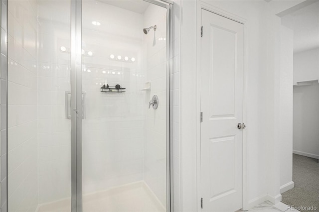 bathroom with a shower stall and baseboards