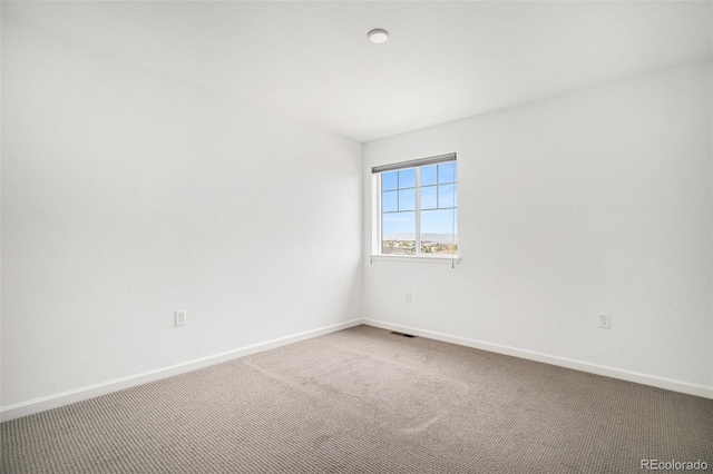 carpeted spare room featuring visible vents and baseboards