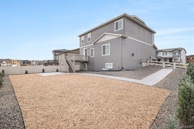 rear view of house with a fenced backyard, a wooden deck, a patio, and stairs