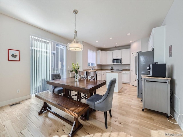 dining space featuring light wood-type flooring and sink