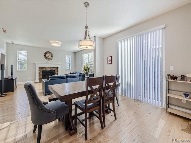 dining space with a stone fireplace and light hardwood / wood-style flooring