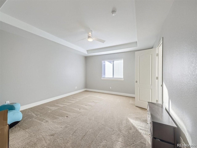 spare room with light colored carpet, ceiling fan, and a raised ceiling