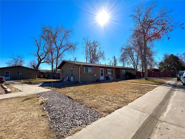 ranch-style house with fence, a front lawn, and brick siding