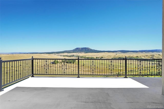 view of patio / terrace featuring a rural view, a mountain view, and a balcony