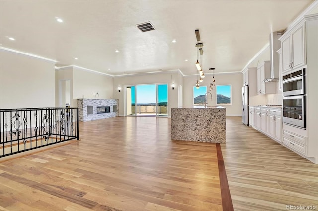 kitchen featuring white cabinetry, hanging light fixtures, light hardwood / wood-style floors, and appliances with stainless steel finishes