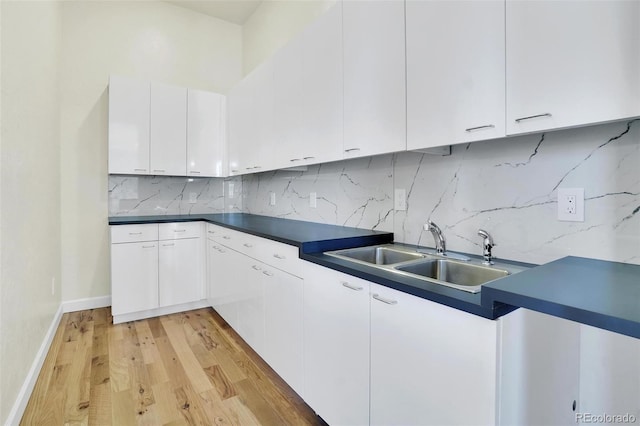 kitchen featuring light wood-type flooring, sink, decorative backsplash, and white cabinets