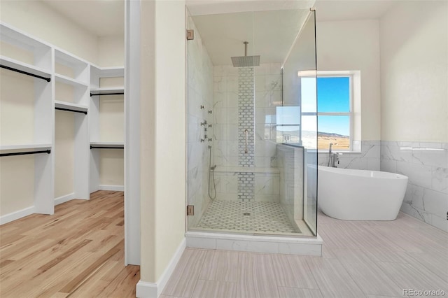 bathroom with shower with separate bathtub, hardwood / wood-style floors, and tile walls