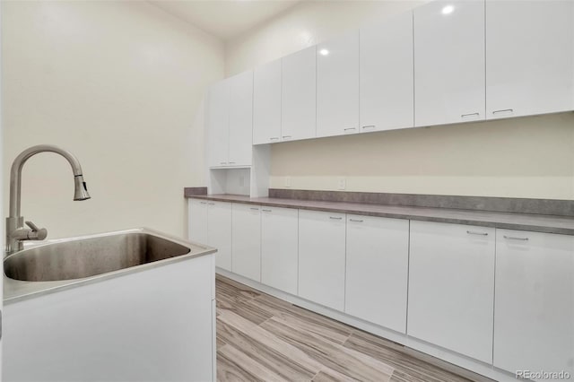 kitchen with white cabinetry, sink, and light hardwood / wood-style floors