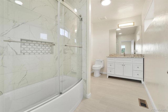 full bathroom with vanity, shower / bath combination with glass door, and toilet