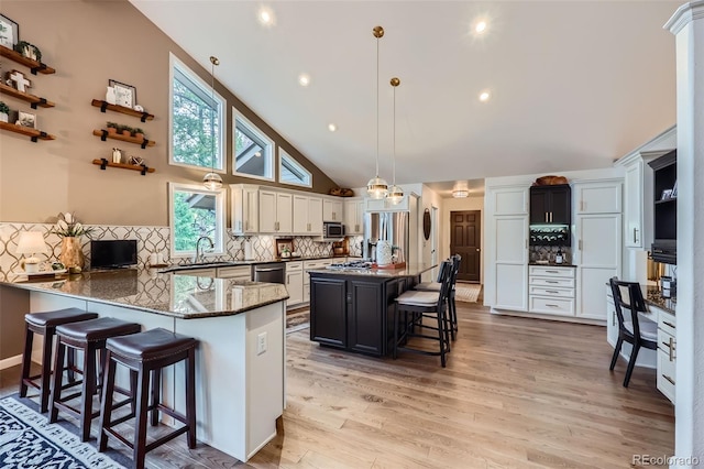 4856 Cheyenne Dr, Larkspur, CO 80118 - kitchen featuring a kitchen breakfast bar, dark stone countertops, tasteful backsplash, a peninsula, and appliances with stainless steel finishes
