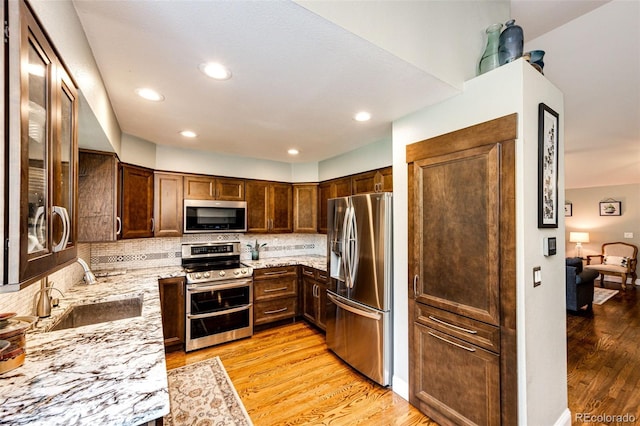 9846 Spring Hill Ln, Highlands Ranch, CO 80129 - kitchen featuring stainless steel appliances, light stone counters, light wood-style floors, tasteful backsplash, and dark brown cabinets