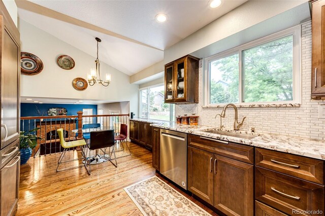 9846 Spring Hill Ln, Highlands Ranch, CO 80129 - kitchen with stainless steel dishwasher, lofted ceiling, light wood-style floors, light stone counters, and tasteful backsplash