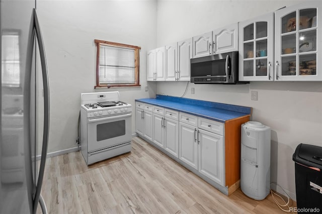 780 Oak St, Hartsel, CO 80449 - kitchen with appliances with stainless steel finishes, light wood-style flooring, glass insert cabinets, and white cabinetry