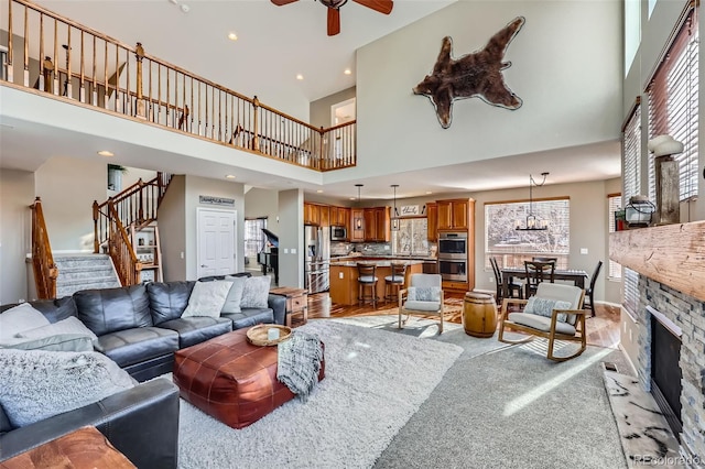 carpeted living room featuring ceiling fan, a high ceiling, a fireplace, and a healthy amount of sunlight