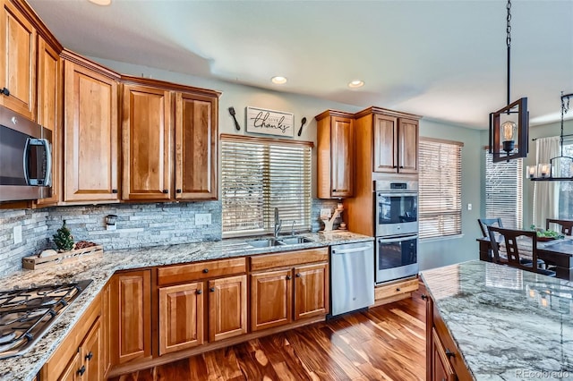 kitchen featuring a wealth of natural light, pendant lighting, stainless steel appliances, tasteful backsplash, and sink