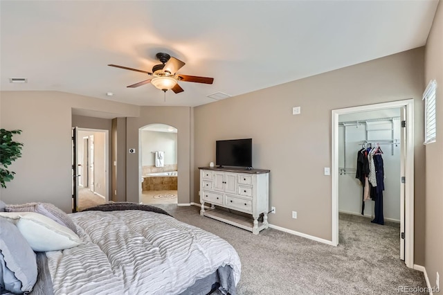 bedroom with a spacious closet, a closet, light colored carpet, ceiling fan, and connected bathroom