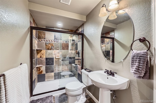 bathroom featuring sink, toilet, and a shower with shower door