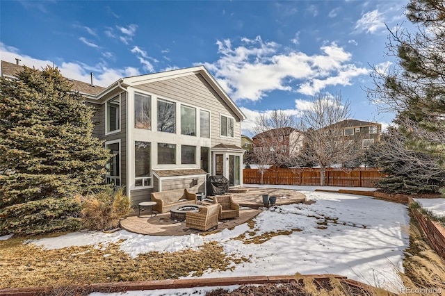 snow covered house with a patio and a fire pit