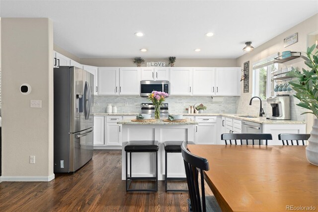 2763 Dharma Ave, Broomfield, CO 80020 - kitchen featuring appliances with stainless steel finishes, a center island, decorative backsplash, white cabinetry, and recessed lighting