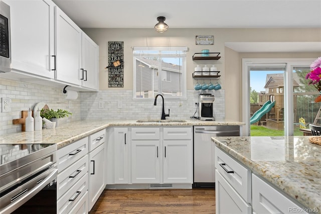 2763 Dharma Ave, Broomfield, CO 80020 - kitchen featuring appliances with stainless steel finishes, dark wood finished floors, decorative backsplash, white cabinetry, and light stone countertops