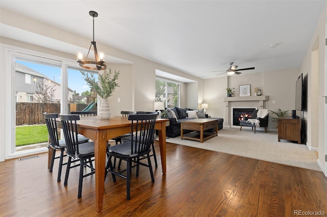 2763 Dharma Ave, Broomfield, CO 80020 - dining space featuring dark wood finished floors, ceiling fan, a glass covered fireplace, and a chandelier