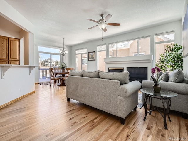 living room featuring ceiling fan with notable chandelier and light hardwood / wood-style flooring