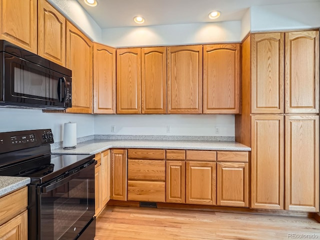 kitchen with light hardwood / wood-style flooring and black appliances