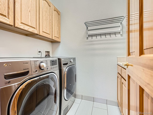 washroom featuring cabinets, light tile patterned flooring, and washing machine and clothes dryer