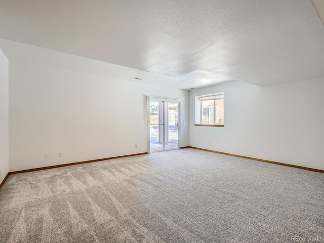 spare room featuring light colored carpet and a textured ceiling