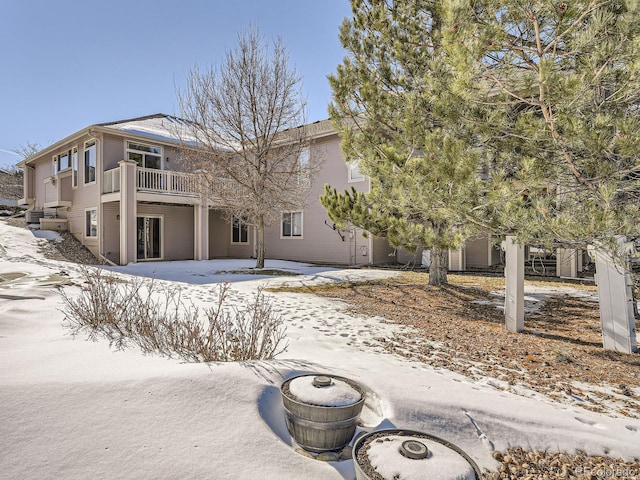 snow covered back of property featuring a balcony