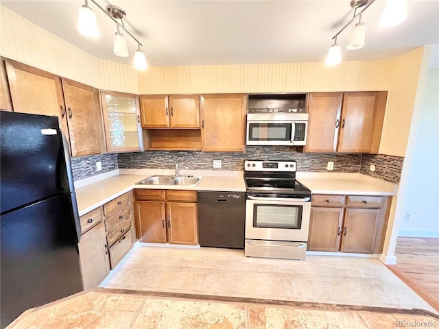 kitchen with tasteful backsplash, sink, hanging light fixtures, and black appliances