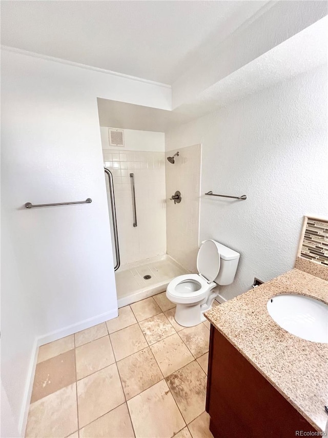 bathroom with vanity, a tile shower, tile patterned floors, and toilet