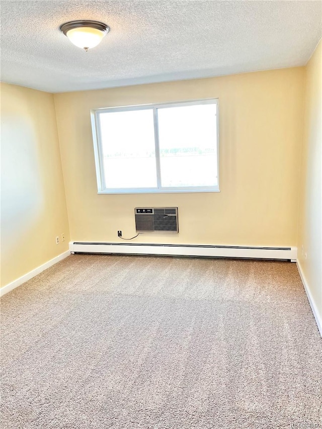 carpeted spare room featuring a healthy amount of sunlight, a textured ceiling, a wall unit AC, and baseboard heating