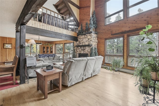 living room featuring wood walls, light hardwood / wood-style floors, high vaulted ceiling, and plenty of natural light