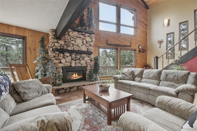 living room featuring beam ceiling, a healthy amount of sunlight, high vaulted ceiling, and a fireplace