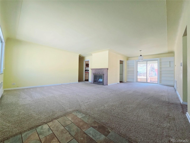 unfurnished living room featuring a brick fireplace and carpet