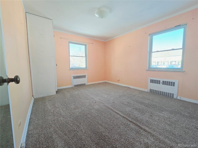 empty room with ornamental molding, radiator heating unit, and carpet floors