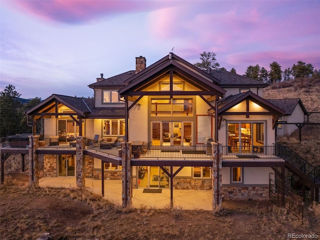 back house at dusk with a balcony and a patio area