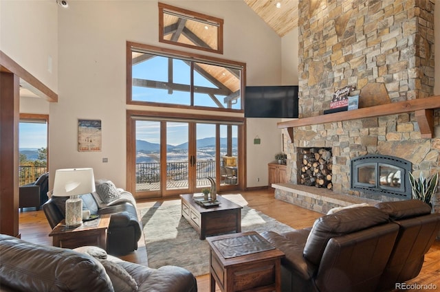 living room featuring a mountain view, a healthy amount of sunlight, a fireplace, and high vaulted ceiling