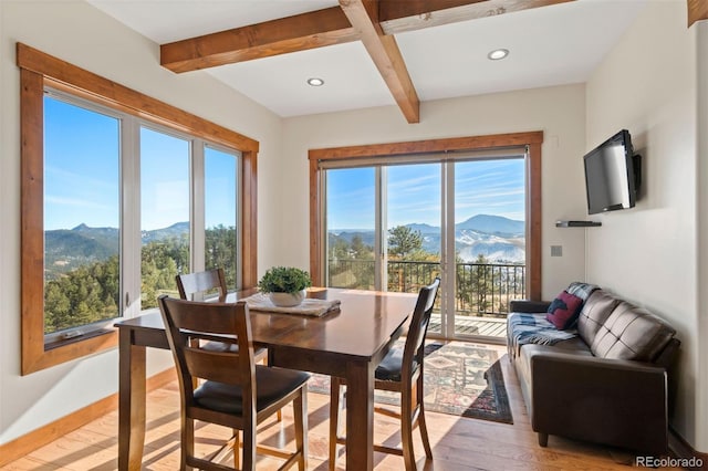 dining room featuring beam ceiling and light wood-type flooring