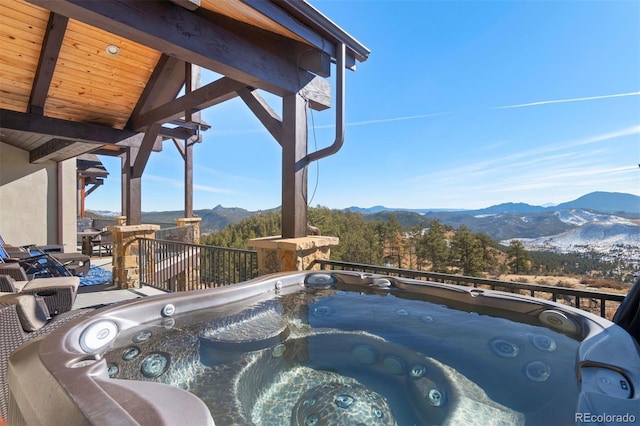 view of swimming pool with a mountain view and a hot tub