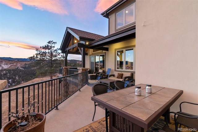 patio terrace at dusk featuring a balcony